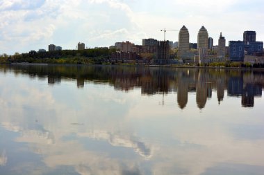 Beautiful background of the city of Dnipropetrovsk (Dnipro), a metropolis with skyscrapers, houses, bridges, green trees standing on the Dnipro River, the country of Ukraine.