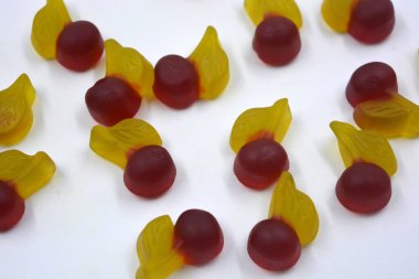 Parlak ve renkli tatlılar, meyveli tatlı jöle şekerler, tatlı meyveler, kirazlar, beyaz arka planda yer alan kirazlar. Lezzetli ve alışılmadık tatlılar, jöle mutluluk ve neşe.