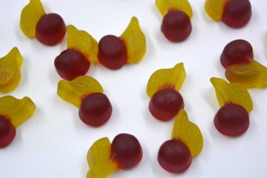 Parlak ve renkli tatlılar, meyveli tatlı jöle şekerler, tatlı meyveler, kirazlar, beyaz arka planda yer alan kirazlar. Lezzetli ve alışılmadık tatlılar, jöle mutluluk ve neşe.