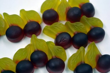 Parlak ve renkli tatlılar, meyveli tatlı jöle şekerler, tatlı meyveler, kirazlar, beyaz arka planda yer alan kirazlar. Lezzetli ve alışılmadık tatlılar, jöle mutluluk ve neşe.