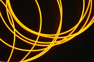 Işıldayan ince kablolardan oluşan parlayan bir kaos. Kaotik olarak ince kablolardan oluşan alışılmadık, benzersiz, parıldayan bir arka plan. Turuncu, sarı, kırmızı parıldayan koşum takımı, ince bir arkaplana yerleştirilmiş ince teller..