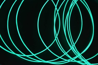 İnce ışık kablolarından oluşan parlayan bir kaos. Alışılmadık, eşsiz, kaotik bir şekilde parlayan ince kablolar, gök mavisi, açık mavi, neon kayış takımı, aydınlatma kablosu, ince bir arkaplana yerleştirilmiş ince kablo..