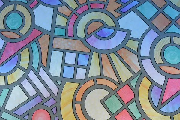 Unusual hand-drawn color film with a mosaic pattern glued to the glass of the balcony of an apartment. Graphic squares, circles, circles, and angles.