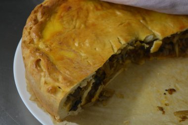 İnce hamurlu ve sebzeli arta kalan turta. Lahana, mantar ve soğan parçaları şık bir Fin mutfağında duruyor..