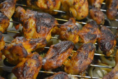 Patates, kabak, kırmızı biber, beyaz soğan, yeşil brokoli gibi sebze tepsisiyle metal bir ağ üzerinde leziz bir şekilde kızartılmış tavuk parçaları..