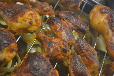 Patates, kabak, kırmızı biber, beyaz soğan, yeşil brokoli gibi sebze tepsisiyle metal bir ağ üzerinde leziz bir şekilde kızartılmış tavuk parçaları..