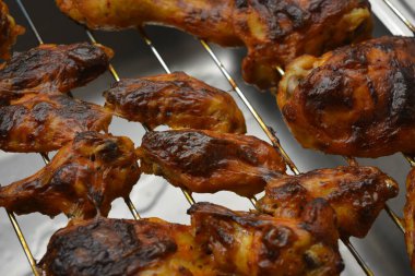 Lezzetli ev yapımı yemekler, bacaklar şeklinde pişmiş tavuk parçaları ve lezzetli kırmızı baharatla marine edilmiş ızgara tavuk kanatları. Metal bir ağ üzerinde ev fırınında pişirilmiş..