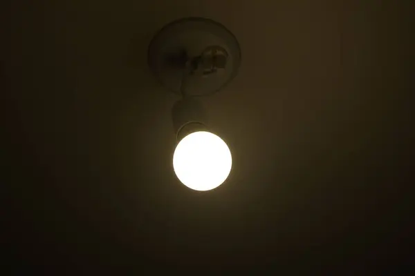 Electric light, white light bulb with white wire, room lighting in white room.