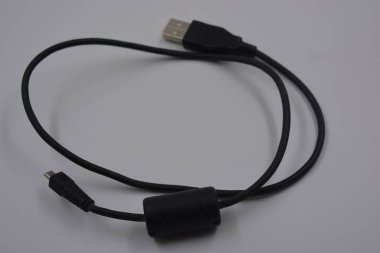 Bilgisayar ekipmanları, uzun siyah bir USB kablosu dijital kameradan normal bir bilgisayara, beyaz plastik arka planda yer alan.