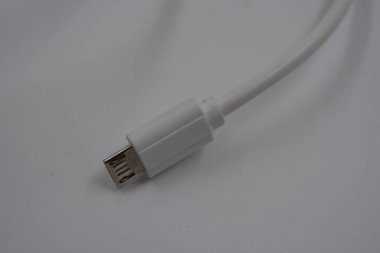 Telefon için bilgisayar teçhizatı uzunluğunda, beyaz mikro USB kablosu, beyaz plastik arka planda bulunan bilgisayar.