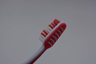 Kişisel hijyen ürünleri, kırmızı ve beyaz tüylü yeni bir plastik diş fırçası, beyaz plastik arka planda kırmızı kauçuk ve diş macunu.. 
