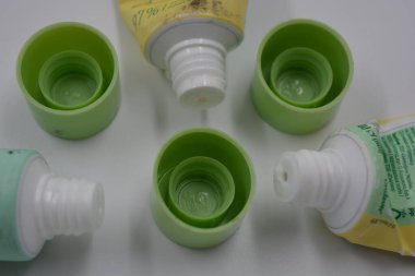 Kadın kozmetik ürünleri, üç plastik, beyaz plastik arka planda üç açık yeşil kapaklı, kullanılmış yüz kremi tüpleri.