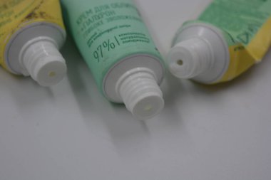 Kadın kozmetik ürünleri, üç plastik, beyaz plastik arka planda üç açık yeşil kapaklı, kullanılmış yüz kremi tüpleri.