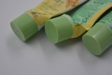 Kadın kozmetik ürünleri, üç plastik, beyaz plastik arka planda üç açık yeşil kapaklı, kullanılmış yüz kremi tüpleri.