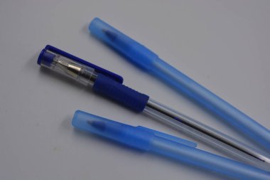Kırtasiye malzemeleri, ofis kırtasiyesi, iki plastik mavi kalem ve bir kalem mavi başlık beyaz arka planda düzenlenmiştir..