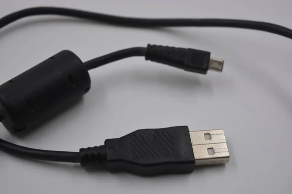 Computer equipment, a long, black micro USB cable from a digital camera to a regular computer, which is located on a white plastic background.