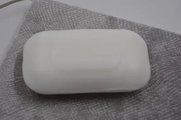 Beautiful, stylish, white bar of soap without logo and name placed on a gray, scaly velvet background.
