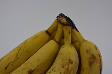 Yiyecek, taze yiyecek, sağlıklı meyve, beyaz plastik arka planda siyah lekeli olgun sarı muz demeti..