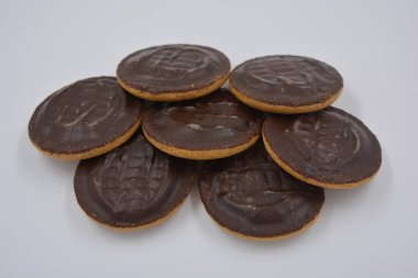 Doğal reçelli lezzetli yuvarlak kek bisküvileri beyaz arka plana yerleştirilmiş doğal çikolatalarla kaplı..