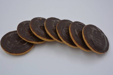 Doğal reçelli lezzetli yuvarlak kek bisküvileri beyaz arka plana yerleştirilmiş doğal çikolatalarla kaplı..