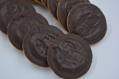 Doğal reçelli lezzetli yuvarlak kek bisküvileri beyaz arka plana yerleştirilmiş doğal çikolatalarla kaplı..