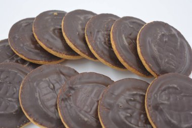 Doğal reçelli lezzetli yuvarlak kek bisküvileri beyaz arka plana yerleştirilmiş doğal çikolatalarla kaplı..