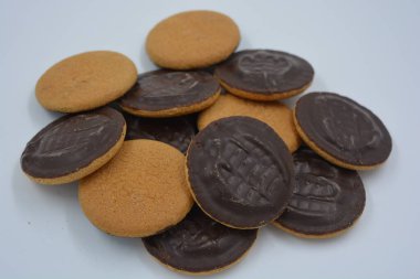 Doğal reçelli lezzetli yuvarlak kek bisküvileri beyaz arka plana yerleştirilmiş doğal çikolatalarla kaplı..