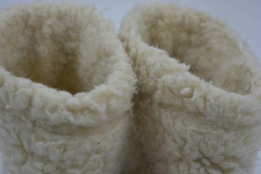 Güzel, sıcak kış ayakkabıları, ev ayakkabıları, Ukraynalı zanaatkarlar tarafından yapılmış siyah tabanlı terlikler beyaz bir arka planda yer alan hafif yünden yapılmış..