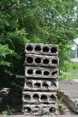 Eski gri yapı malzemeleri, bir sürü metal çimento, doğada ağaçların olduğu yere beton yapı taşları..