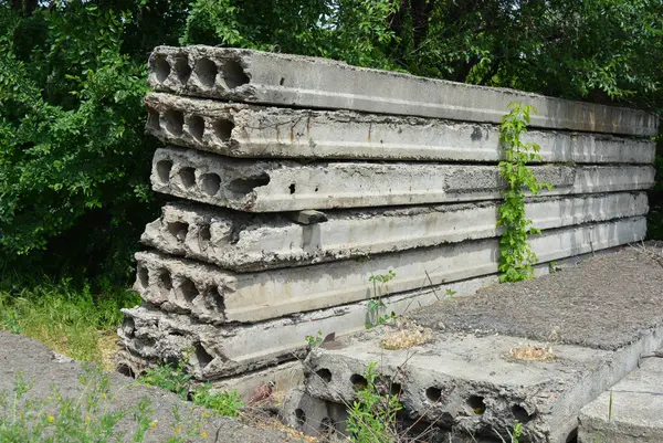 Eski gri yapı malzemeleri, bir sürü metal çimento, doğada ağaçların olduğu yere beton yapı taşları..