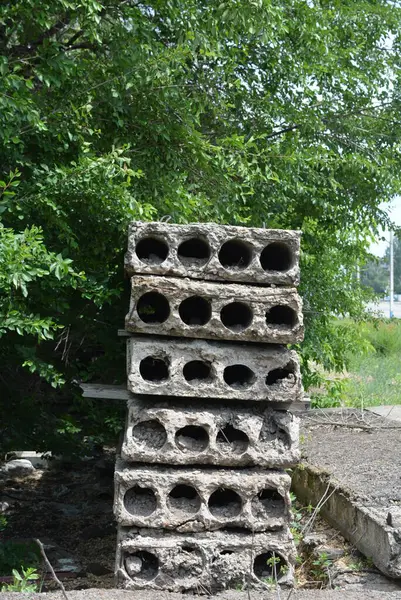 Eski gri yapı malzemeleri, bir sürü metal çimento, doğada ağaçların olduğu yere beton yapı taşları..
