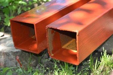 İnşaat malzemeleri, inşaat ve onarım malzemeleri. Uzun, kalın, metalik profil taze kahverengi boyayla kaplı. Özel bir arsada profil oluşturuluyor.