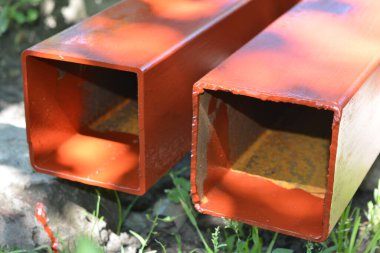 İnşaat malzemeleri, inşaat ve onarım malzemeleri. Uzun, kalın, metalik profil taze kahverengi boyayla kaplı. Özel bir arsada profil oluşturuluyor.