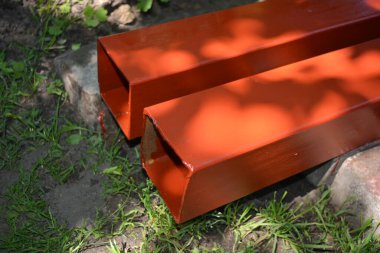 İnşaat malzemeleri, inşaat ve onarım malzemeleri. Uzun, kalın, metalik profil taze kahverengi boyayla kaplı. Özel bir arsada profil oluşturuluyor.