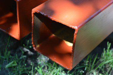 İnşaat malzemeleri, inşaat ve onarım malzemeleri. Uzun, kalın, metalik profil taze kahverengi boyayla kaplı. Özel bir arsada profil oluşturuluyor.