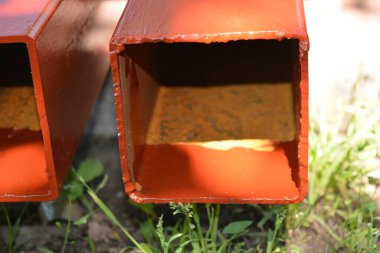 İnşaat malzemeleri, inşaat ve onarım malzemeleri. Uzun, kalın, metalik profil taze kahverengi boyayla kaplı. Özel bir arsada profil oluşturuluyor.