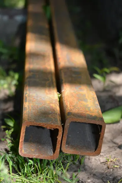 Building materials, equipment for construction and repair works. A long, thick, metal profile with a small amount of red rust located on the site.