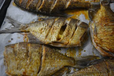 Lezzetli ve sağlıklı, fırında balık, limonlu Carassius beyaz parşömen kağıdıyla siyah bir yemek tepsisi üzerinde.