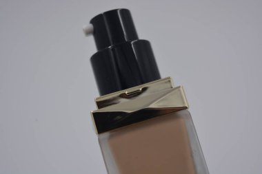 Kadın kozmetik ürünleri, aksesuarlar, nemlendirme, bakım için temel, beyaz plastik arka planda mat siyah kapaklı güzel bir cam şişede yüz bakımı..