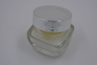 Kadın kozmetik ürünleri, aksesuarlar, nemlendirme için beyaz krem, bakım, gümüş kapaklı güzel cam bir kavanozda yüz bakımı ve beyaz plastik bir arka plan..