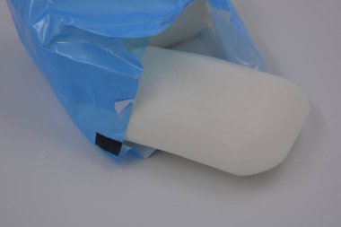 Hijyen ürünleri, ev kozmetik ürünleri, bakım ürünleri, mavi polietilen ambalajlı beyaz sabun çubukları beyaz arka planda düzenlenmiştir.