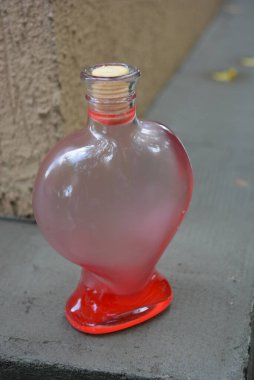 Güzel cam bir kap kalp şeklinde hafif bir ahşap tıpası ve kırmızı bir sıvı caddede duruyor..