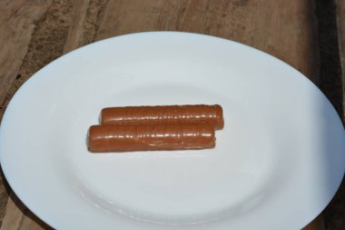 Şekerler, çikolatayla kaplanmış çubuklar, beyaz cam bir tabağa yerleştirilmiş karaciğer ve karamel..