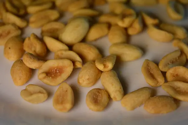 Healthy foods, health, nuts, salted toasted peanuts are arranged interestingly on a white glass plate.