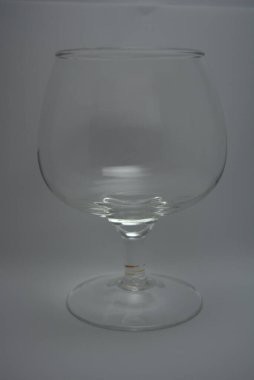 Beyaz parlak arka planda konyak, brendi ve viski için şık bir bardak bulunur..