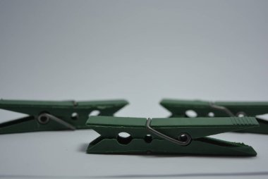 Günlük hayatta kullanılan olağan şeyler bunlar. Beyaz arkaplana yerleştirilmiş güzel yeşil plastik mandallar.