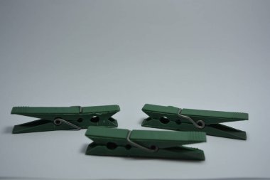 Günlük hayatta kullanılan olağan şeyler bunlar. Beyaz arkaplana yerleştirilmiş güzel yeşil plastik mandallar.