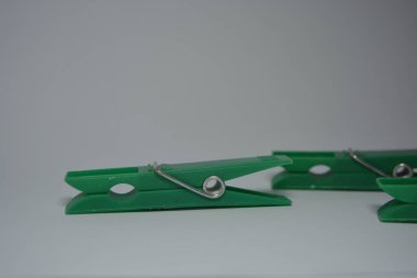 Günlük hayatta kullanılan olağan şeyler bunlar. Beyaz arkaplana yerleştirilmiş güzel yeşil plastik mandallar.