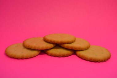 Kahvaltı, lezzetli ve sağlıklı yiyecekler, tuzlu bisküviler, pembe arka planda dizilmiş yuvarlak krakerler..