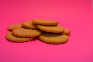 Kahvaltı, lezzetli ve sağlıklı yiyecekler, tuzlu bisküviler, pembe arka planda dizilmiş yuvarlak krakerler..